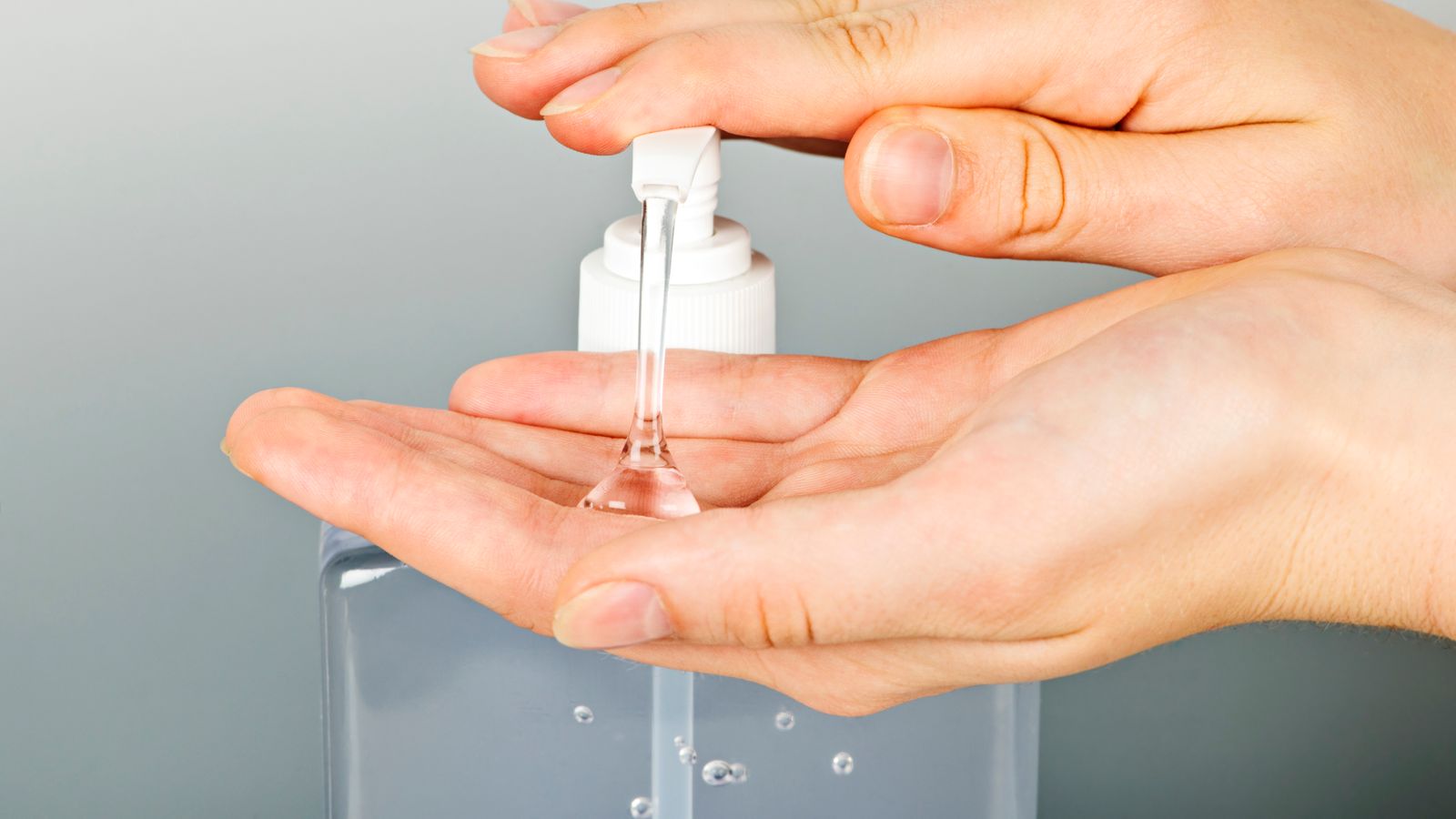 A person pumping hand sanitizer from a dispense onto their hands.